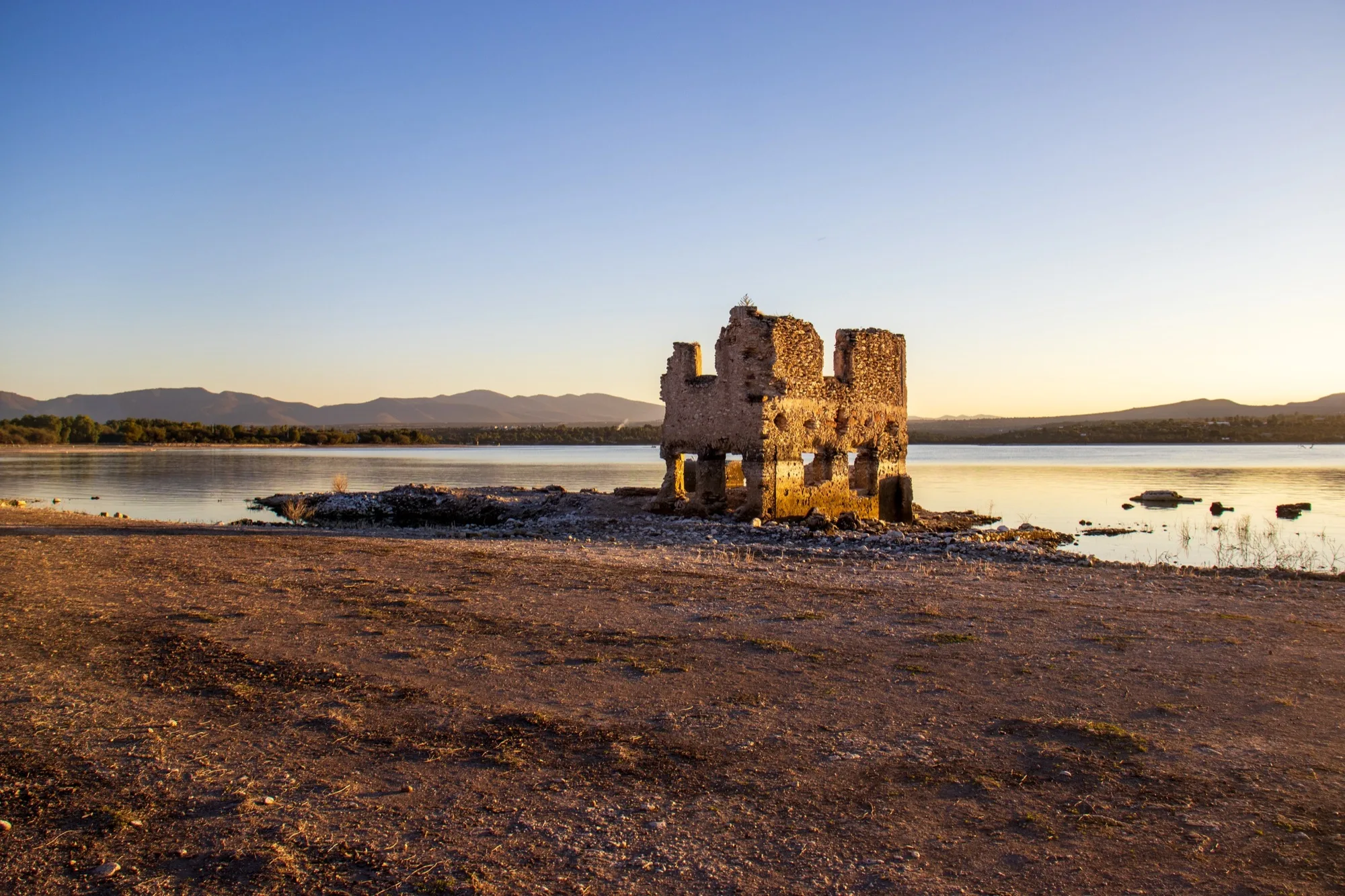 Paisaje al atardecer con ruinas junto a un lago